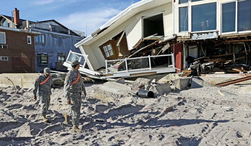 National Guardsmen Spc. Ivan Pimentel (left) and Pfc. Harry Cadet walk past a house on the beach in the Rockaways on New York’s Long Island on Thursday that was ravaged by Superstorm Sandy in October. They were going door-to-door to determine if residents needed portable heaters or other items in the wake of Sandy. (Associated Press)
