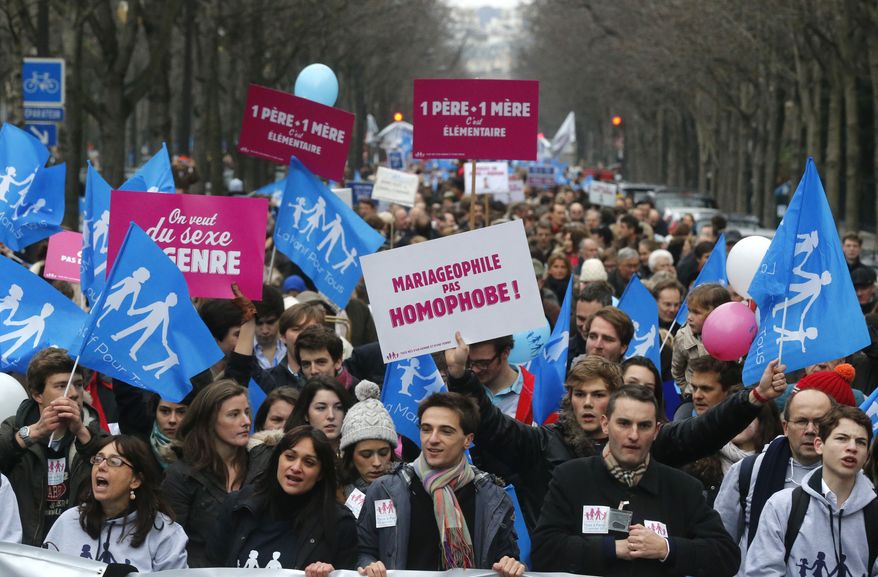 Demonstrators carry red placards with the words 'One father, one mother, it's obvious" in Paris on Sunday, Jan. 13, 2013, as thousands of protesters mobilized against the French president's plan to legalize gay marriage. The placard at center reads: "Pro-marriage, not anti-gay." (AP Photo/Michel Euler)