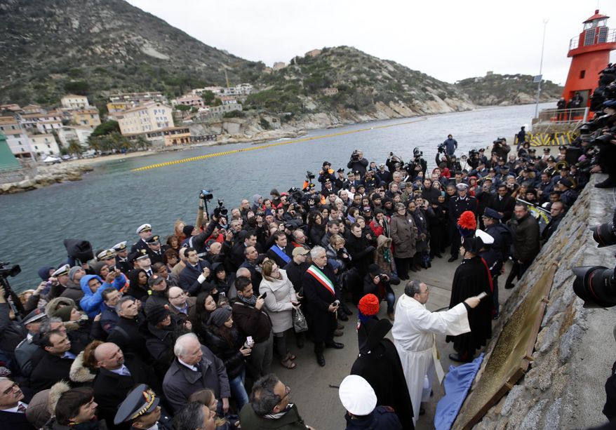 A priest blesses a commemorative plaque bearing the names of the 32 people who died in the Costa Concordia shipwreck after the plaque was unveiled on Tuscany's Isola del Giglio on Sunday, Jan. 13, 2013. Survivors of the shipwreck and relatives of those who died marked the first anniversary of the grounding Sunday. (AP Photo/Gregorio Borgia)