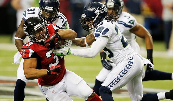 Atlanta Falcons running back Michael Turner (33) his hit by Seattle Seahawks free safety Earl Thomas (29) and Seattle Seahawks strong safety Kam Chancellor (31) during the first half of an NFC divisional playoff NFL football game Sunday, Jan. 13, 2013, in Atlanta. (AP Photo/John Bazemore)