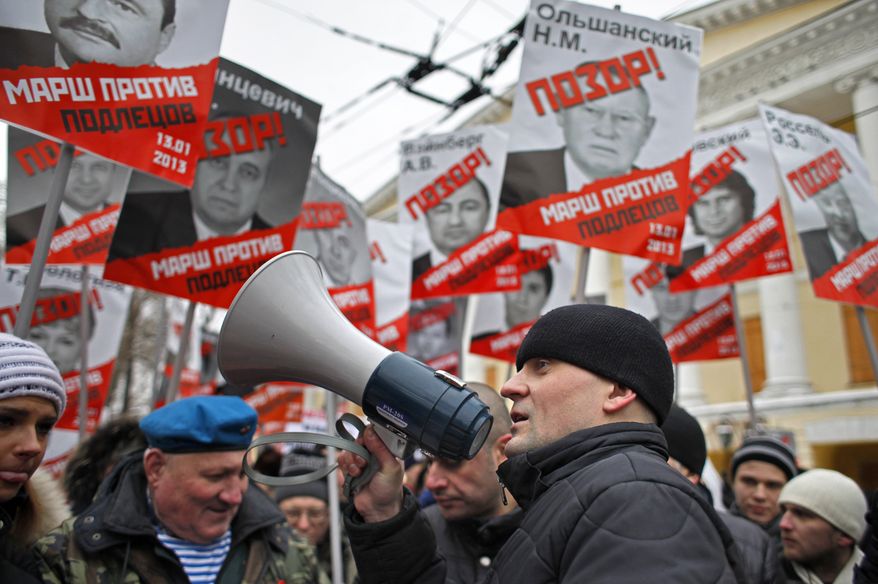 Opposition leader Sergei Udaltsov (foreground) speaks during a demonstration in Moscow on Sunday, Jan. 13, 2013, as thousands of people protested against Russia's new law banning Americans from adopting Russian children. The posters have the word "Shame" written in red over the faces of Russian lawmakers and proclaim Sunday's demonstration as a "March Against the Scum" who enacted the law. (AP Photo/Alexander Zemlianichenko)