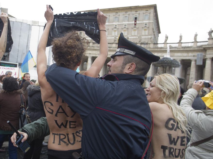 Police officers stop members of a group of four women who went topless to protest the Vatican's opposition to gay marriage in St. Peter's Square at the Vatican on Sunday, Jan. 13, 2013. Police quickly took the women away, and the pope appeared not to have been disturbed as he delivered his traditional prayer from his studio window overlooking the piazza. On their bare backs, the women had painted the slogans "In Gay We Trust" and "Shut Up. (AP Photo/Angelo Carconi)