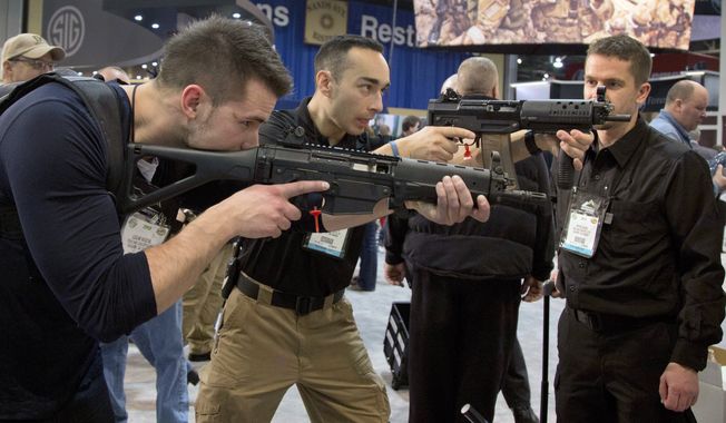 ** FILE ** Firearms instructors Logan Martin (left) and Andres Gonzalez of Calgary, Alberta, look through the sights of Sig Sauer Swat Patrol AR rifles during the 35th annual SHOT Show on Tuesday, Jan. 15, 2013, in Las Vegas. (AP Photo/Julie Jacobson)