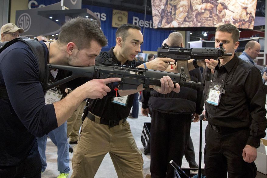 ** FILE ** Firearms instructors Logan Martin (left) and Andres Gonzalez of Calgary, Alberta, look through the sights of Sig Sauer Swat Patrol AR rifles during the 35th annual SHOT Show on Tuesday, Jan. 15, 2013, in Las Vegas. (AP Photo/Julie Jacobson)