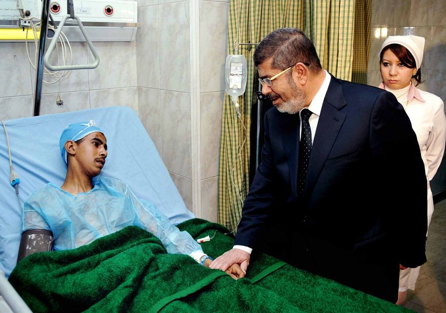 Egyptian President Mohammed Morsi (right) visits a victim receiving treatment at a military hospital in Cairo on Jan. 15, 2013, following a train crash in Badrasheen, 40 kilometers (25 miles) south of Cairo. At least 19 people died and more than 100 were injured when two railroad passenger cars derailed, health officials say. (Associated Press/Egyptian Presidency)
