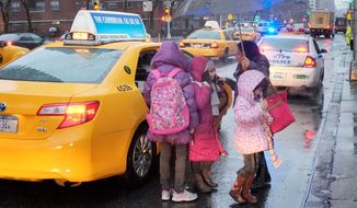 A woman takes her children by taxi to Public School 33 in New York on Wednesday as more than 8,000 school bus drivers and aides go on strike over job protection. Children who rely on the buses include 54,000 special education students and others who live far from schools or transportation. (Associated Press)