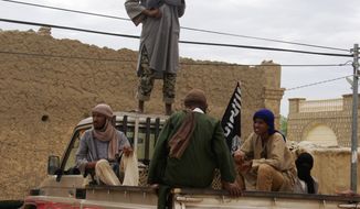 Fighters from the al Qaeda-linked Ansar Dine stand guard in Timbuktu, Mali, as they prepare to publicly lash a member of the Islamic Police found guilty of adultery. (Associated Press)