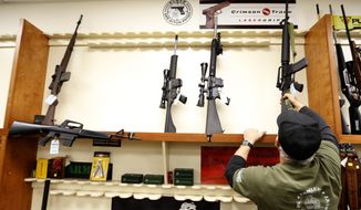Mike Fiota, manager at Duke&#x27;s Sport Shop in New Castle, Pa., replaces Jan. 15, 2013, one of five used military style rifles — all that are available — into a rack that usually has more than twenty new models for sale. Fiota says the few there are on consignment from individuals. (Associated Press)