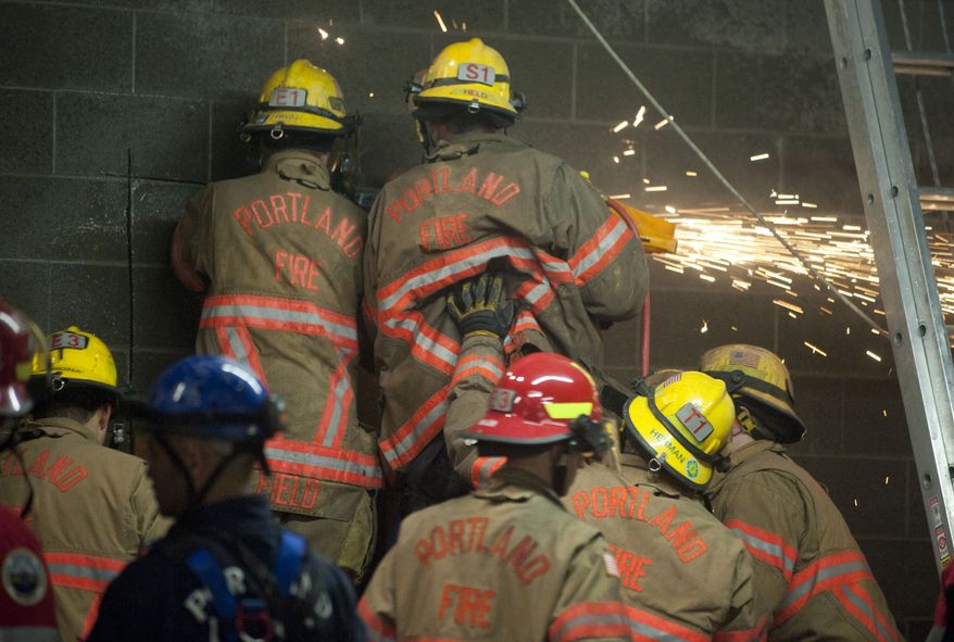 Firefighters work to free a woman who fell part of the way down a 20-foot wall and got stuck between two buildings in Portland, Ore., on Wednesday, Jan. 16, 2013. (AP Photo/The Oregonian, Brent Wojahn)