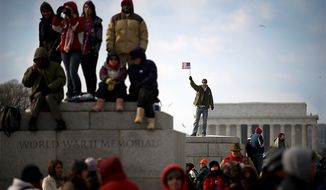 ** FILE ** A man waves a flag from atop part of the World War II Memorial after the swearing in of President Barack Obama on inauguration day on the National Mall in Washington D.C., Tuesday, Jan. 20, 2009. (Allison Shelley / The Washington Times)

