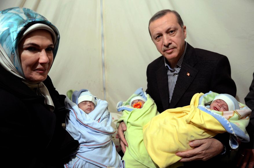 ** FILE ** In this photo provided by Turkish Prime Minister's Press Service, Turkish Prime Minister Recep Tayyip Erdogan, and his wife Emine Erdogan hold newly born babies during a visit to a Syrian refugee camp in Sanliurfa, Turkey, Sunday, Dec. 30, 2012. Erdogan repeated a call on Syrian President Bashar Assad to step down. (AP Photo/Kayhan Ozer)