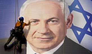 ** FILE ** In this Thursday, Jan. 17, 2013, file photograph, a worker hangs a huge poster with an image of Israel&#39;s Prime Minister Benjamin Netanyahu overlooking the Ayalon freeway in Tel Aviv, Israel. (AP Photo/Ariel Schalit, File)
