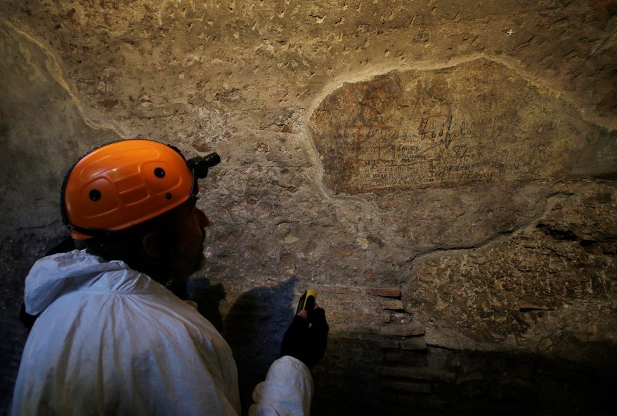 A restorer shows journalists an ancient graffiti recently discovered inside a gallery of Rome's Colosseum, Friday, Jan. 18, 2013. (AP Photo/Gregorio Borgia)