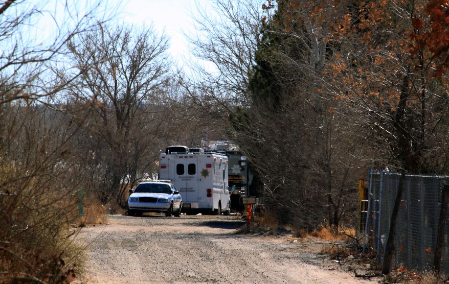 Bernalillo County authorities are stationed outside a home south of Albuquerque, N.M., on Sunday, Jan. 20, 2013, where two adults and three children were found shot to death. (AP Photo/Susan Montoya Bryan)
