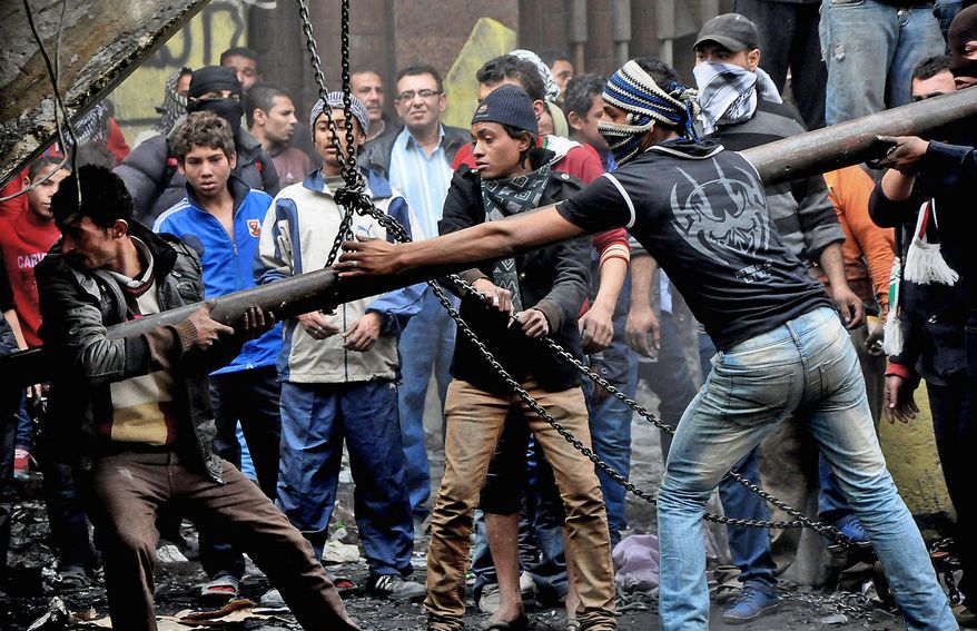 Egyptian protesters try to tear down a cement wall built to prevent them from reaching parliament and the Cabinet building near Tahrir Square in Cairo on Jan. 24, 2013. (Associated Press)
