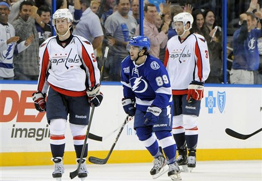 Tampa Bay Lightning left wing Cory Conacher, center, skates between Washington Capitals defensemen Mike Green, left, and Tom Poti after his goal during the third period of an NHL hockey game Saturday, Jan. 19, 2013, in Tampa, Fla. The Lightning won 6-3. (AP Photo/Brian Blanco)