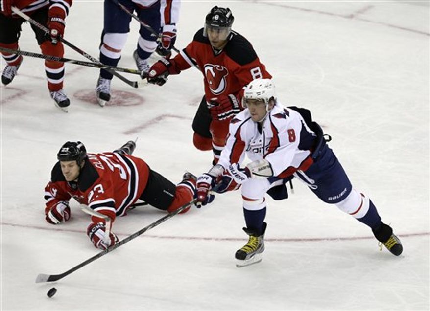 New Jersey Devils' David Clarkson (23) falls to the ice as Washington Capitals' Alex Ovechkin, of Russia, (8) slaps the puck away during overtime in an NHL hockey game Friday, Jan. 25, 2013, in Newark, N.J. The Devils won 3-2. (AP Photo/Mel Evans)
