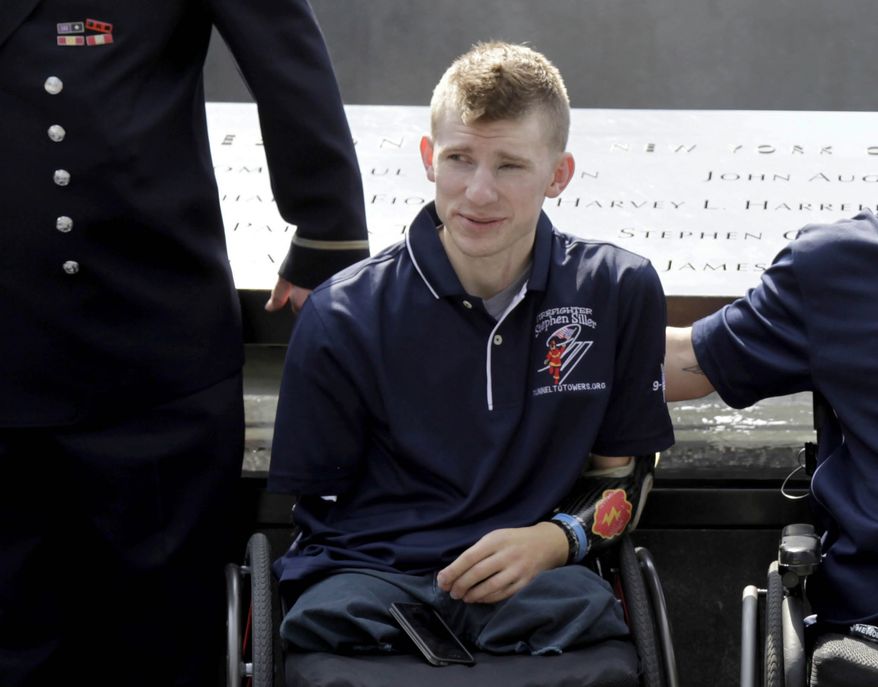 Army Sgt. Brendan Marrocco of Staten Island, N.Y., wearing a prosthetic arm, poses for a picture at the 9/11 Memorial in New York on July 4, 2012. (AP Photo/Seth Wenig)