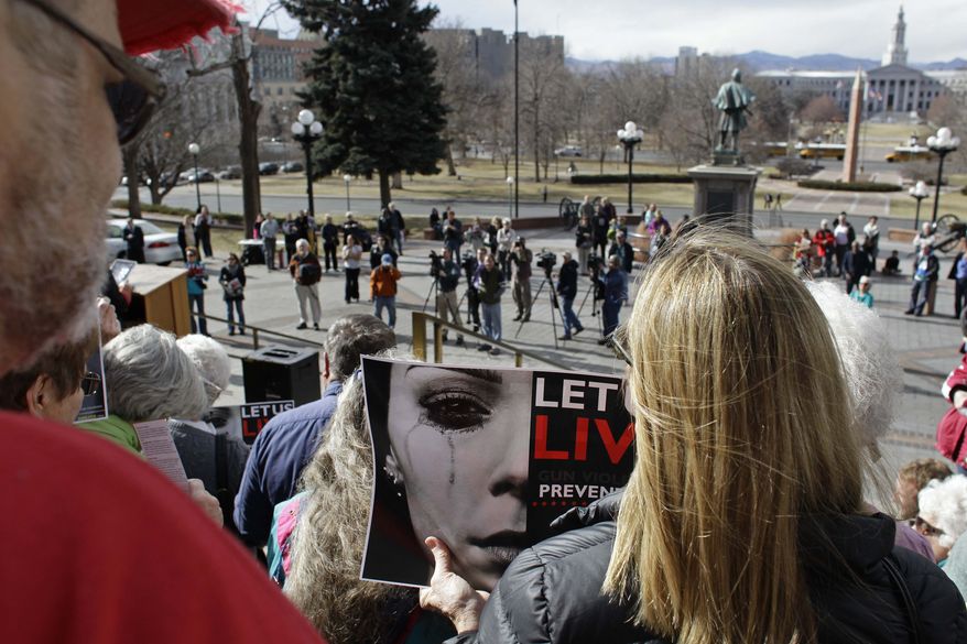 A woman carries a poster promoting a gun control movement during a rally on the steps of the Colorado State Capitol, in Denver, Monday, Jan. 28, 2013. Colorado's long-anticipated gun control debate is getting under way, with some Democrats planning to pursue gun control measures including expanded background checks and a possible statewide assault-weapons ban. At the same time, Republicans were arguing Monday for a bill designed to allow school employees to carry concealed weapons at work. (AP Photo/Brennan Linsley)