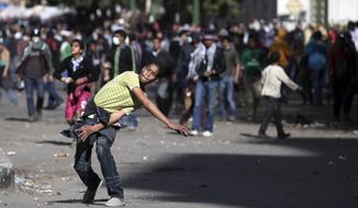 An Egyptian protester throws stones at riot police, not seen, during clashes near Tahrir Square in Cairo, Egypt, Wednesday, Jan. 30, 2013. (AP Photo/Khalil Hamra)