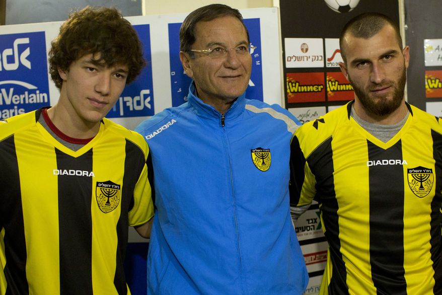 Beitar Jerusalem F.C. soccer coach Eli Cohen, center, poses for the media with new Beitar players Gabriel Kadiev, left, and Zaur Sadayev, right, during a press conference in Jerusalem, Wednesday, Jan. 30, 2013. The arrival of Zaur Sadayev and Gabriel Kadiev to Beitar Jerusalem's squad comes amid rising tensions. The team's fans chanted anti-Muslim slogans at a recent game and unfurled a sign protesting the Chechens' arrival. (AP Photo/Bernat Armangue)
