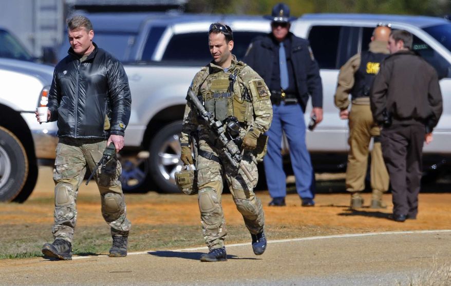Law officers at the Dale County hostage scene in Midland City, Ala., on Thursday morning, Jan. 31, 2013. A gunman holed up in a bunker with a 5-year-old hostage has kept law officers at bay since the standoff began when he killed a school bus driver and dragged the boy away, authorities said. (AP Photo/Montgomery Advertiser, Mickey Welsh)