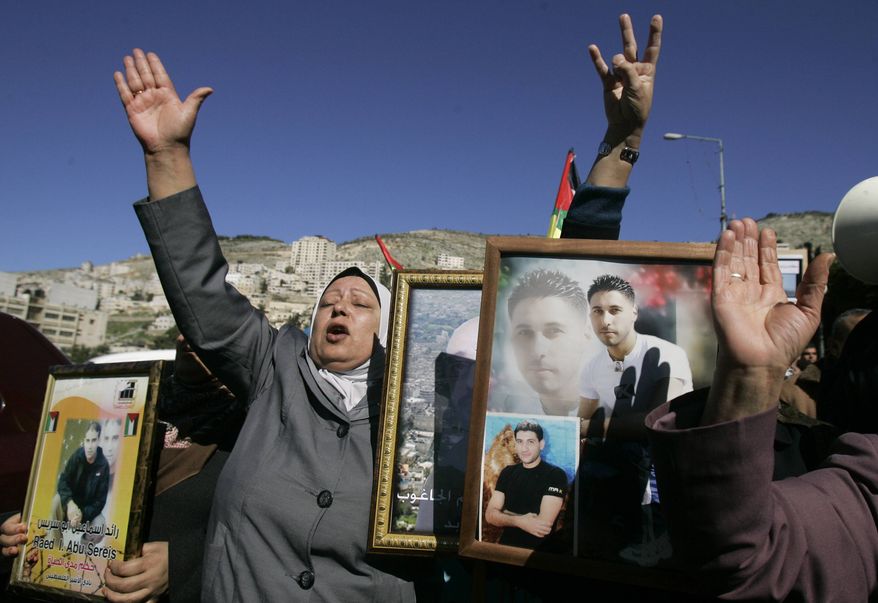 Palestinian women hold pictures of prisoners jailed in Israel during a rally calling for their release, in the West Bank city of Nablus, Monday, Feb. 4, 2013. Israeli forces arrested 20 members of the Palestinian militant group Hamas, including three lawmakers, in a raid early Monday in the West Bank, Hamas officials said. (AP Photo/Nasser Ishtayeh)