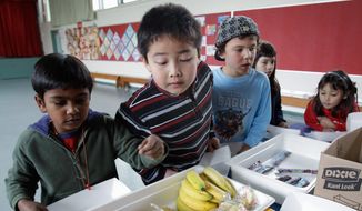 ** FILE ** Second-grader Jonathan Cheng (center) looks at fruits and vegetables during a school lunch at Fairmeadow Elementary School in Palo Alto, Calif., on Dec. 2, 2010. (Associated Press)