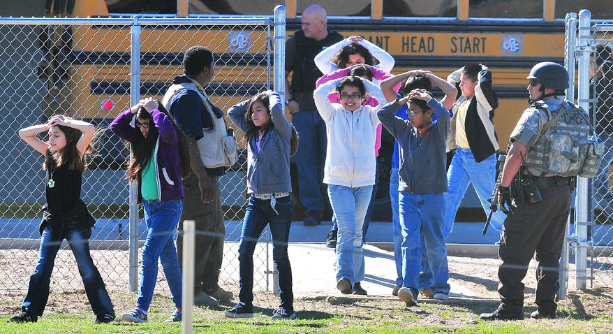 Students from Salida Del Sol Elementary School are evacuated to the school cafeteria by police officers after three schools went into lockdown on Tuesday, Feb. 5, 2013, in Yuma, Ariz. The unconfirmed report of a person with a gun initially prompted the lockdown, but no gun was found. (AP Photo/The Yuma Sun, Craig Fry)