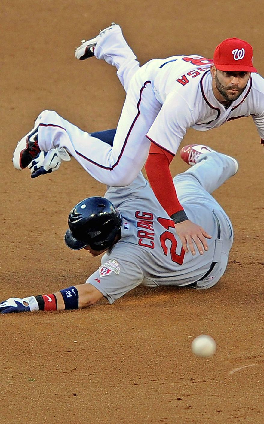 Washington Nationals second baseman Danny Espinosa, top, leaps over St. Louis Cardinals' Allen Craig as he throws out Cardinals batter Yadier Molina at first base in the sixth inning of Game 4 of the National League division baseball series on Thursday, Oct. 11, 2012, in Washington. Craig was safe at second base. (AP Photo/Nick Wass)
