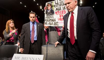 Anti-war protesters yell and hold signs as John O. Brennan arrives to testify before the Senate Select Committee on Intelligence at a hearing on Capitol Hill in Washington on Thursday, Feb. 7, 2013, on his nomination to head the Central Intelligence Agency. (Andrew Harnik/The Washington Times)