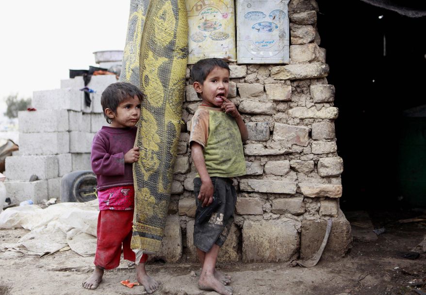 Children stand in front of their house at a compound for displaced people in Baghdad's southeastern Zaafaraniyah district, Wednesday, Feb. 6, 2013. An estimated 1.55 million people are currently displaced inside Iraq due to sectarian violence that threatened their lives. (AP Photo/ Hadi Mizban)