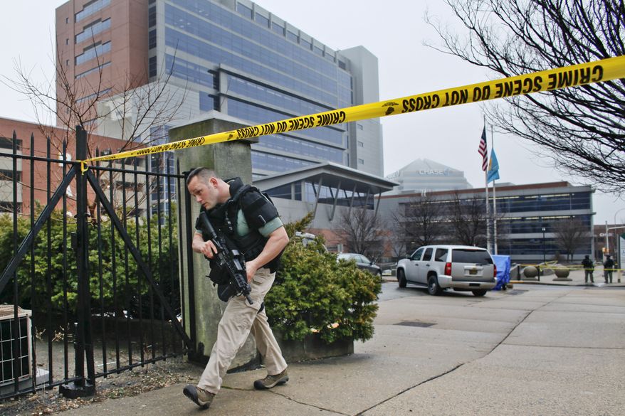 A law enforcement official makes his way around the perimeter outside the New Castle County Courthouse in Wilmington, Del., on Feb. 11, 2013, after three people in a shooting at the courthouse, including the gunman. (Associated Press)