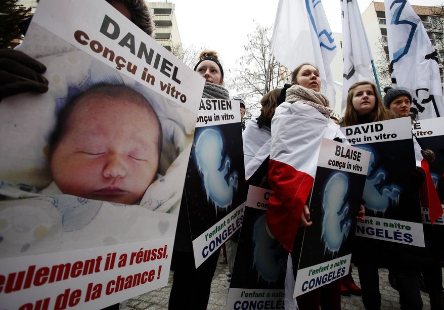 **FILE** French demonstrators take to the streets Jan. 13, 2013, to protest against French President Francois Hollande's plan to legalize marriage and adoption for gay people in Paris, with placards reading "Made in vitro" (on left) and "Frozen child to be born." (Associated Press)