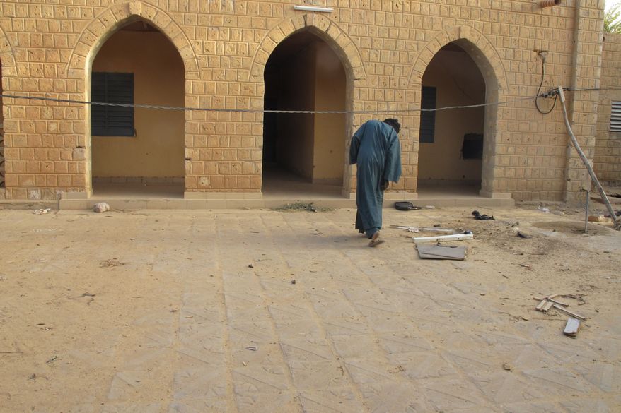 **FILE** Neighborhood resident Mohamed Alassane ducks under a wire Feb. 6, 2013, to enter the Ministry of Finance&#x27;s Regional Audit Department in Timbuktu, Mali, a site used by al Qaeda-linked Islamists for more than a year. (Associated Press)