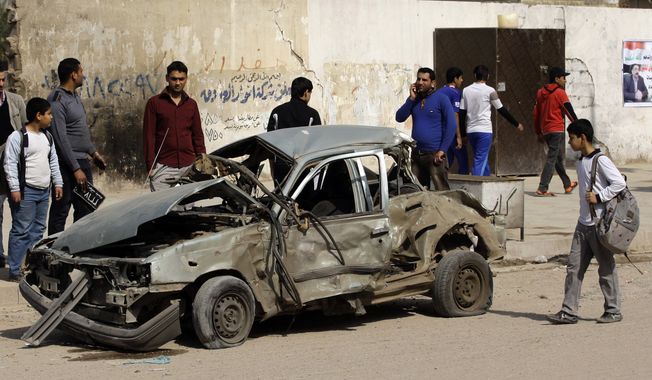 Iraqis inspect a destroyed car at the scene of a car bomb attack in eastern Baghdad on Sunday, Feb. 17, 2013. A series of car bombs exploded within minutes of one another as Iraqis were out shopping in and around the capital, killing and wounding scores of people, police said. (AP Photo/Khalid Mohammed)