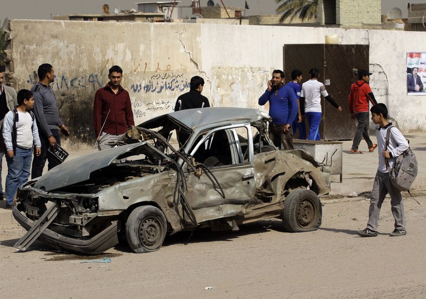 Iraqis inspect a destroyed car at the scene of a car bomb attack in eastern Baghdad on Sunday, Feb. 17, 2013. A series of car bombs exploded within minutes of one another as Iraqis were out shopping in and around the capital, killing and wounding scores of people, police said. (AP Photo/Khalid Mohammed)