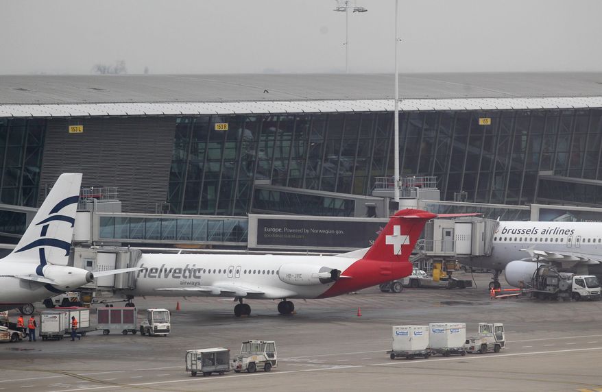 Baggage carts make their way past a Helvetic Airways aircraft from which millions' of dollars worth of diamonds were stolen on the tarmac of Brussels international airport, Tuesday, Feb. 19, 2013. (AP Photo/Yves Logghe)