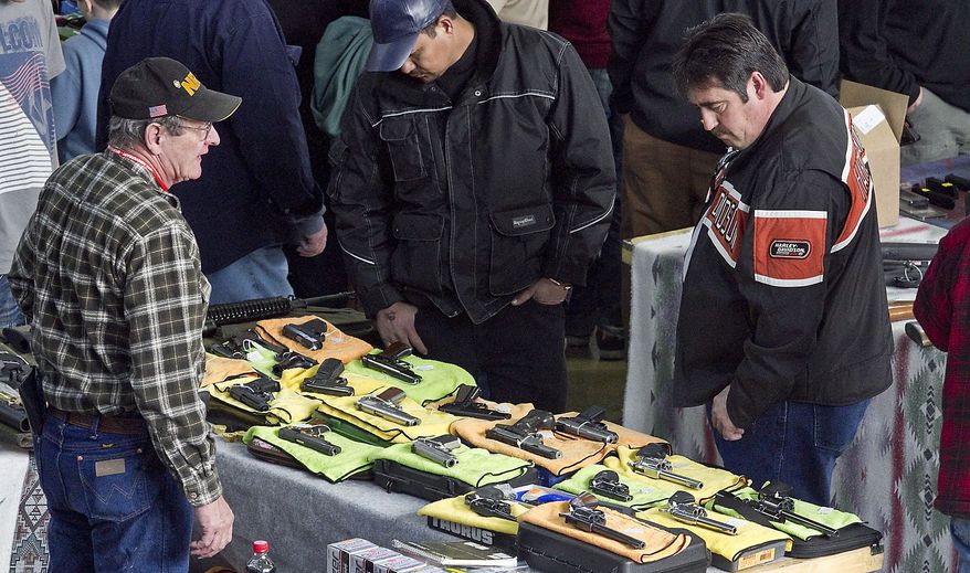 ** FILE ** People look at firearm displays at the Sports Connection Gun Show at the Modern Living Building at State Fair Park in Yakima, Wash., on Saturday, Feb. 16, 2013. (AP Photo/Yakima Herald-Republic, TJ Mullinax)