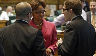 ** FILE ** Rep. Rhonda Fields, D-Aurora, center, talks with Rep. Joseph Salazar, left, and House Speaker Mark Ferrandino, right, D-Denver, about her bill on limiting the size of ammunition magazines at the Capitol in Denver on Friday, Feb. 15, 2013. (AP Photo/Ed Andrieski)

