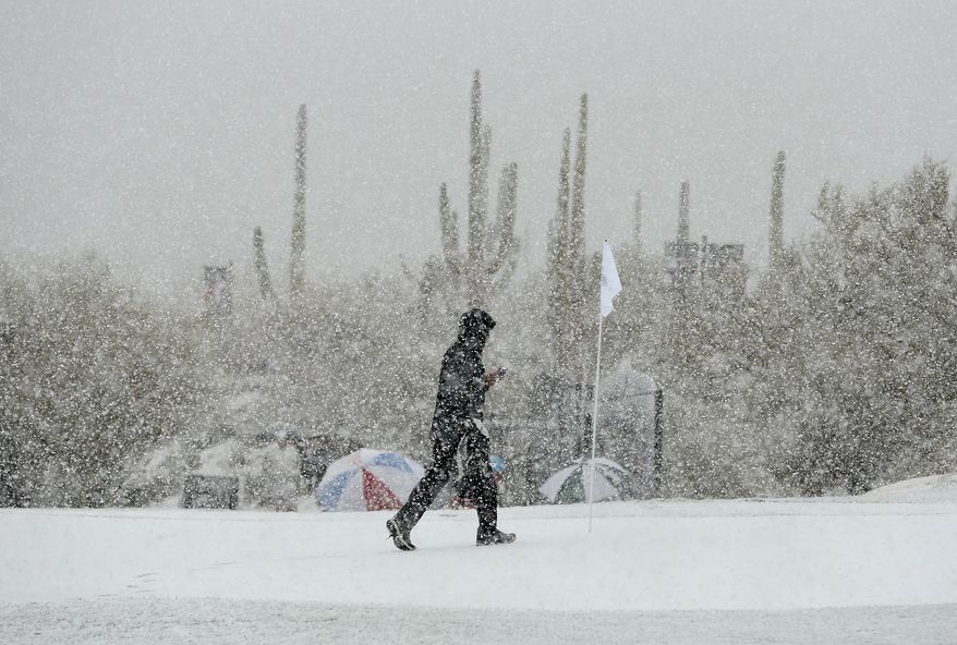 A volunteer walks along the practice green as snow falls during the Match Play Championship golf tournament, Wednesday, Feb. 20, 2013, in Marana, Ariz. Play was suspended. (AP Photo/Ross Franklin)