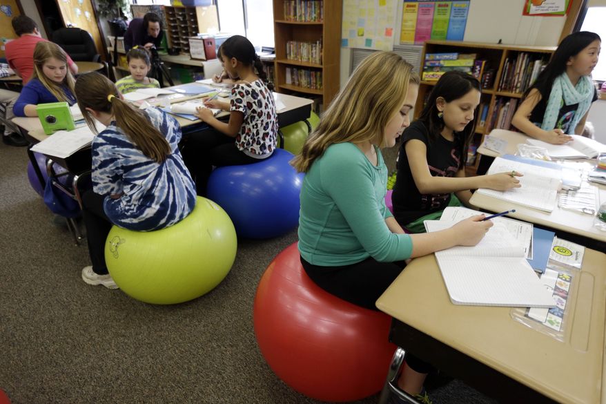 Students in Robbi Giuliano&#x27;s fifth-grade class sit on yoga balls as they complete their assignments at Westtown-Thornbury Elementary School Monday, Feb. 4, 2013, in West Chester, Pa. By making the sitter work to stay balanced, the balls force muscle engagement and increased blood flow, leading to more alertness. (AP Photo/Matt Rourke)
