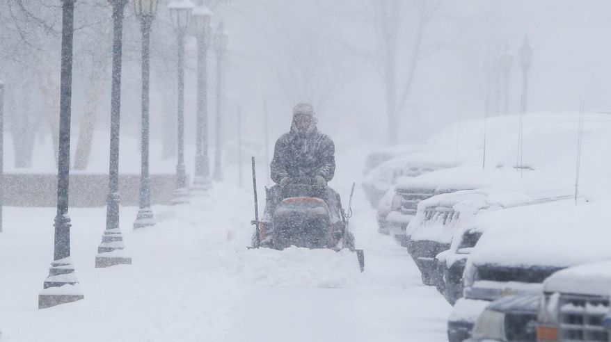 A man clears snow from the sidewalks around Friends University in Wichita, Kan. as heavy snow falls on Wednesday morning, Feb. 20, 2013. A large winter storm moved in over the early morning hours and is expected to last until Thursday evening. (AP Photo/The Wichita Eagle, Travis Heying)