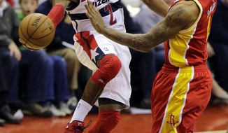 Washington Wizards guard John Wall (2) passes the ball as he is guarded by Houston Rockets forward Greg Smith (4) in the second half of an NBA basketball game, Saturday, Feb. 23, 2013, in Washington. The Wizards won 105-103. (AP Photo/Alex Brandon)