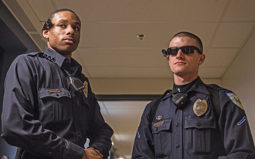 Officer Carl Johnson and Officer Matthew Jordan, of the Laurel Police Department, wear Taser Axon Flex cameras. The department is testing the cameras before deploying them in the field. The cameras are meant to protect police officers from complaints. (Andrew S. Geraci/The Washington Times)
