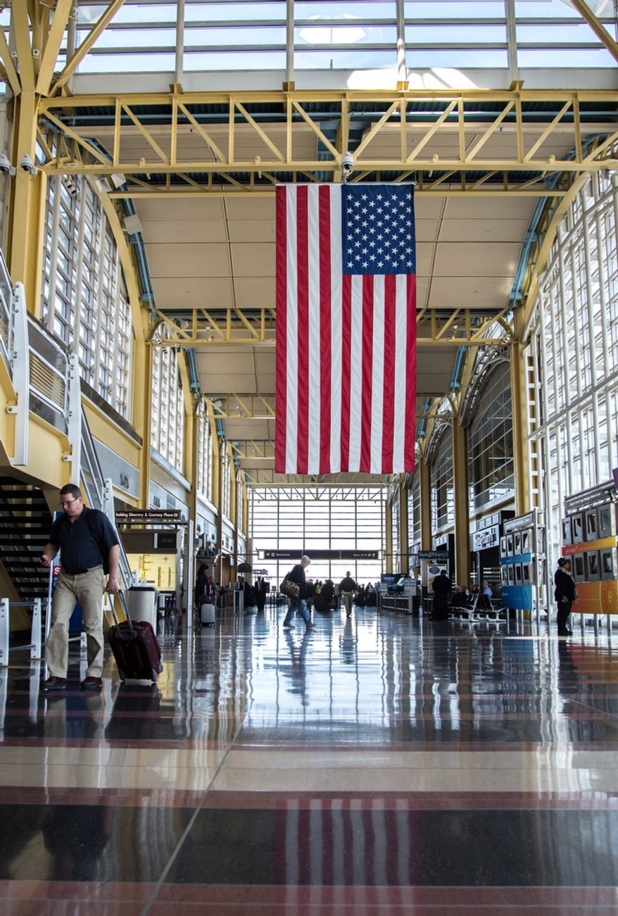 An U.S. flag hangs from the rafters at Reagan National Airport in Washington on Feb. 25, 2013, as travelers pass through. (Andrew S. Geraci/The Washington Times)