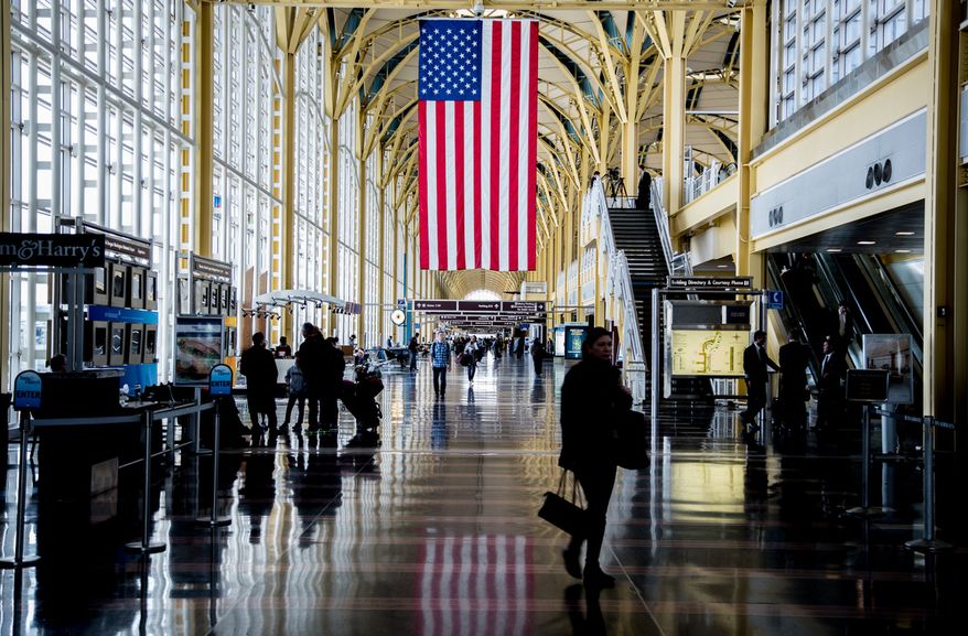 An U.S. flag hangs from the rafters at Reagan National Airport in Washington on Feb. 25, 2013, as travelers pass through. (Andrew S. Geraci/The Washington Times)