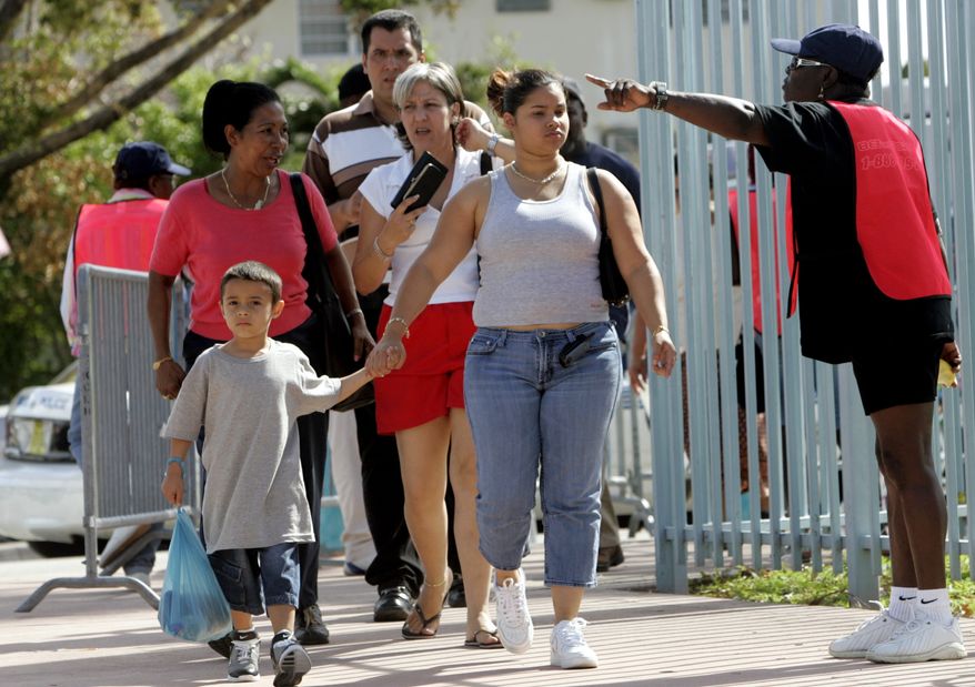 **FILE** An employee of the Florida Department of Children and Families (right) directs applicants for food stamps at a food stamp emergency assistance center at the Orange Bowl in Miami on Nov. 9, 2005. (Associated Press)