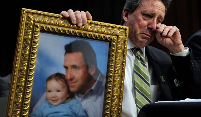 Neil Heslin holds a picture of himself and his young son Jesse, who was 6 when he was killed at Sandy Hook Elementary, while testifying Wednesday before the Senate Judiciary Committee on the Assault Weapons Ban of 2013. (Associated Press)