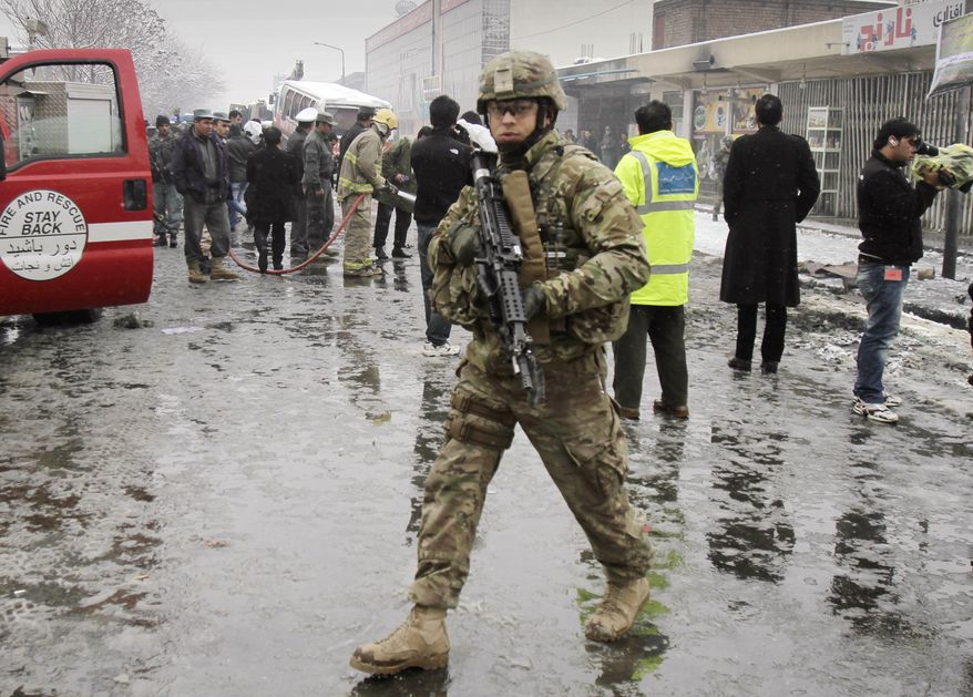 A U.S. soldier with the NATO forces patrols at the scene of a suicide attack in Kabul, Afghanistan, on Wednesday, Feb. 27, 2013. A man wearing a black overcoat and carrying an umbrella as a shelter against the heavy snow crossed a street in the Afghan capital toward an idling bus filled with Afghan soldiers, where he lay down and wiggled underneath. Then an explosion engulfed the undercarriage of the bus in flames. (AP Photo/Ahmad Jamshid)